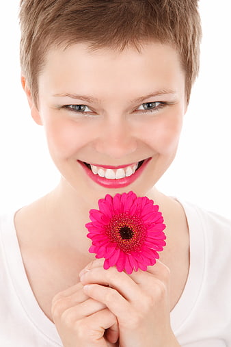 Happy woman with short hair holding pink gerbera flower