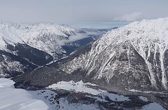 Aerial view of snow-covered mountain peaks and deep forested valley