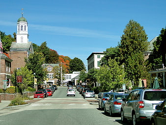 Quaint New England Town Street With Historic Church And Parked Cars
