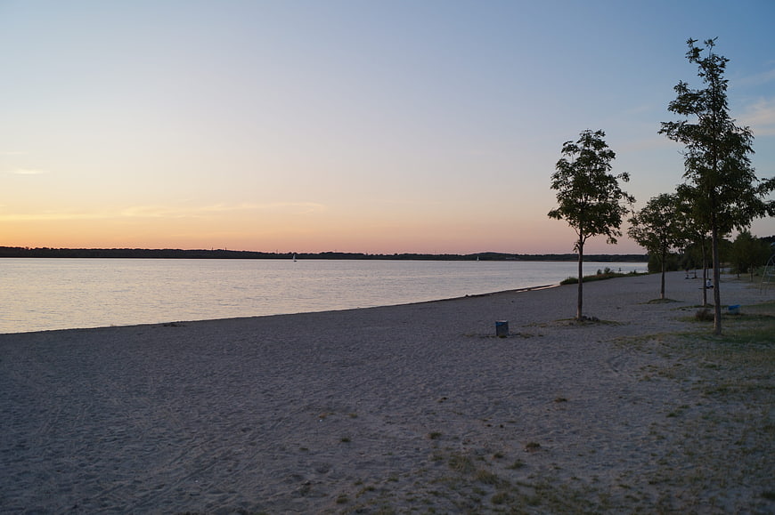 Serene Sunset Lake Beach with Trees and Calm Water