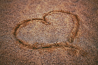 Heart drawn in sand texture close up