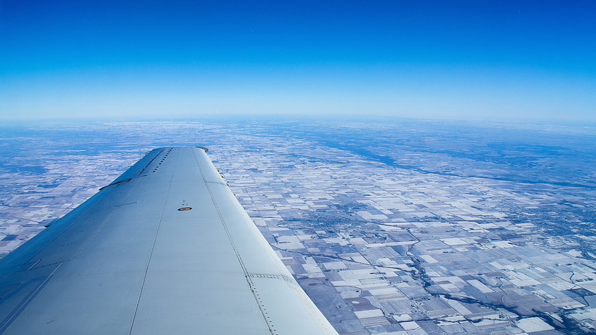 Airplane wing view over snowy winter landscape from above
