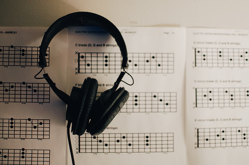 Black headphones resting on guitar chord chart sheet music