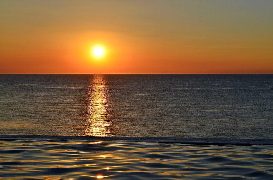 Sunset over ocean with infinity pool reflection