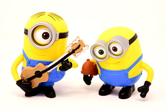 Two Minion Toy Figures Playing Guitar And Drums On White Background