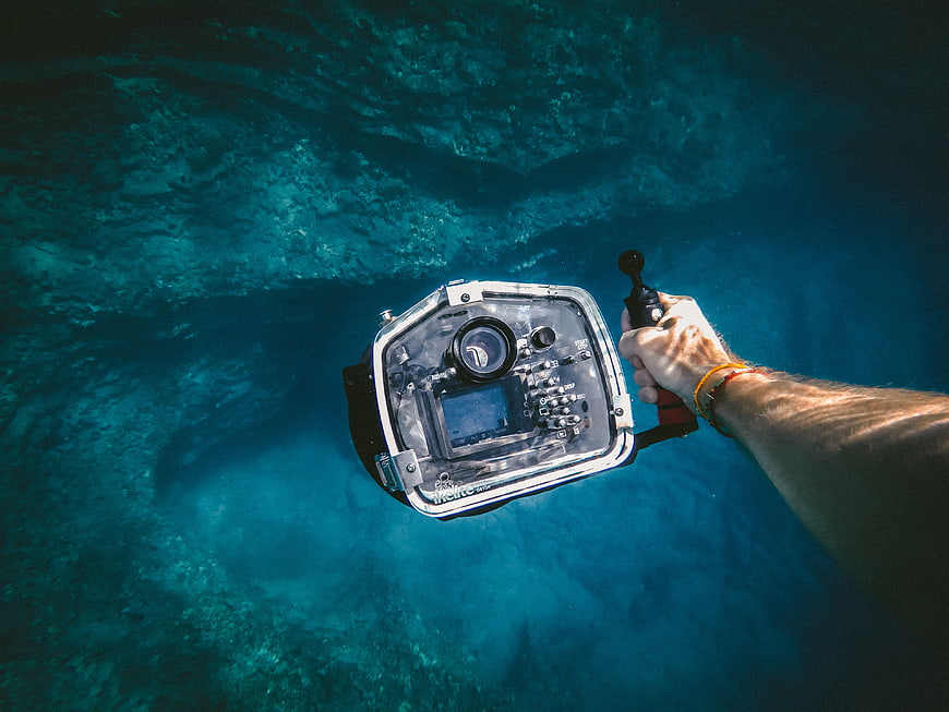 Underwater Photographer Holding Waterproof Camera Housing in Blue Ocean
