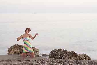 Woman in Rainbow Dress Kneeling on Beach