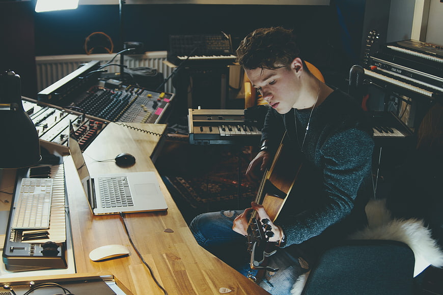 Young musician playing guitar in recording studio