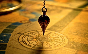 Antique brass pendulum over vintage map compass rose
