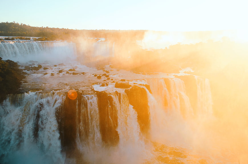 Majestic Waterfall at Golden Hour with Mist and Sunlight