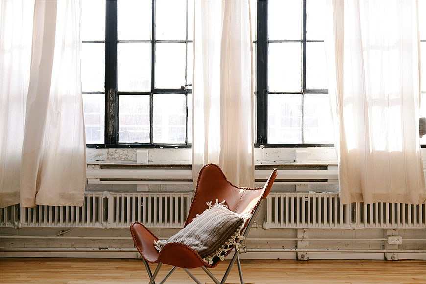 Modern leather butterfly chair in loft with large windows