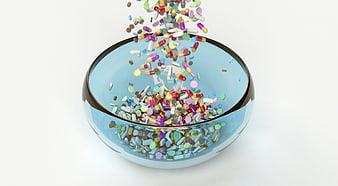 Colorful Pills Falling Into Glass Bowl On White Background