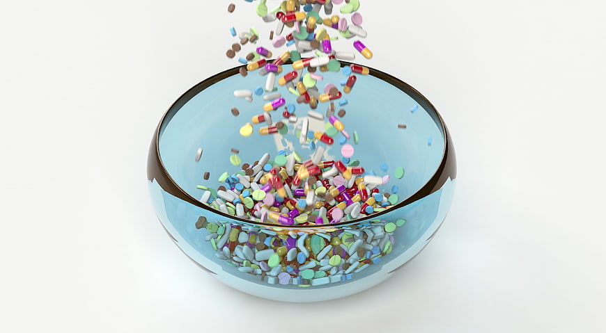 Colorful Pills Falling Into Glass Bowl On White Background