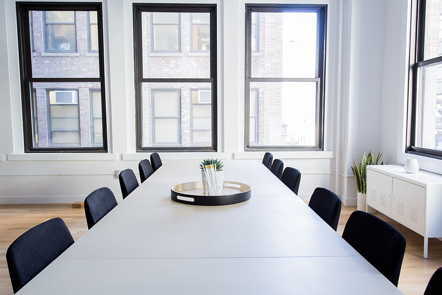 Modern minimalist conference room with white table and large windows