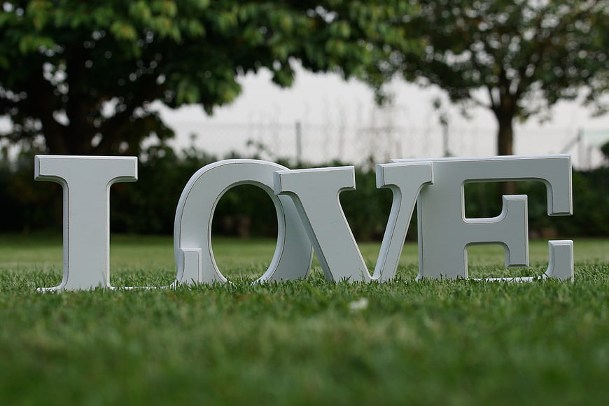 White LOVE letters on green grass in park