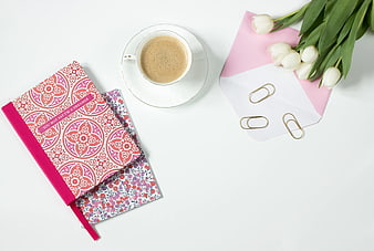 Flat lay of coffee, notebooks, and white tulips on white background