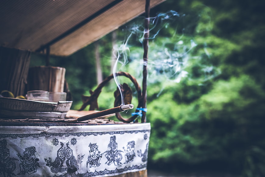 Burning incense stick on traditional altar in forest
