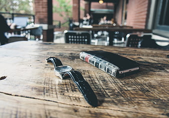 Vintage watch and smartphone on rustic wooden cafe table