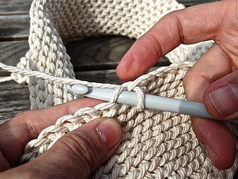 Close-up of hands crocheting with thick beige yarn