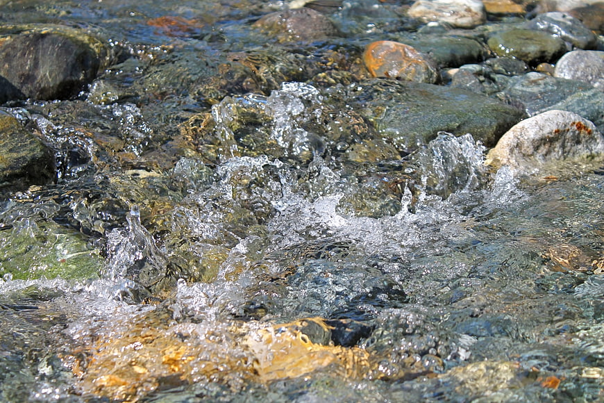 Crystal clear water flowing over smooth river stones