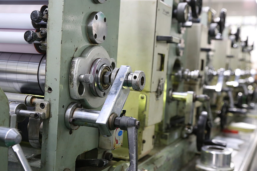 Close-up of industrial offset printing machine rollers and mechanical components