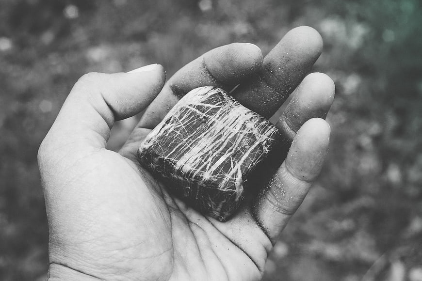 Hand holding a textured black and white stone cube