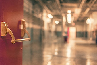 Close-up of brass door handle on red door with blurred hallway background
