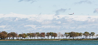 Commercial Airplane Landing Over Lake and Autumn Trees