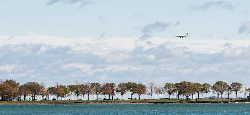 Commercial Airplane Landing Over Lake and Autumn Trees