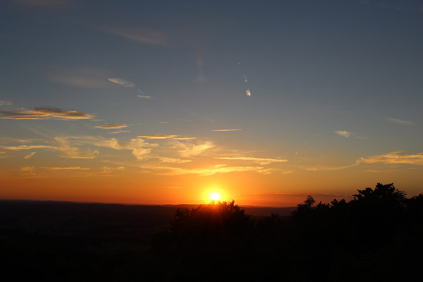 Golden sunset over silhouetted forest landscape with clouds
