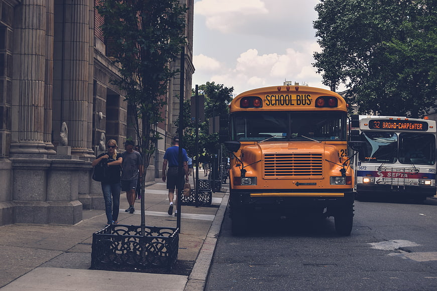 Yellow School Bus on City Street with Pedestrians