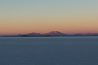 Serene Frozen Lake Landscape with Distant Mountains at Sunset