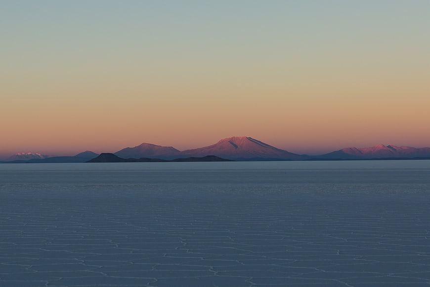 Serene Frozen Lake Landscape with Distant Mountains at Sunset