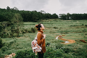 Woman with Backpack Enjoying Nature in Green Field