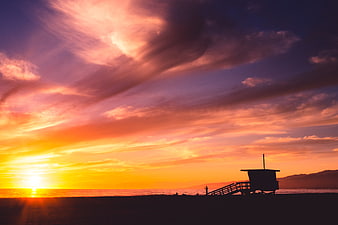Vibrant Sunset Over Beach with Lifeguard Tower Silhouette
