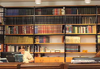 Senior Woman Working At Computer In Public Library Reading Room