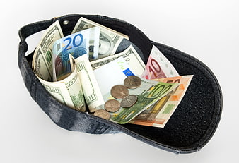 Black baseball cap filled with US dollar bills and euro banknotes