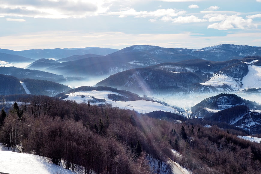 Snowy mountain landscape with morning mist and forest
