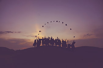 Silhouette of Graduates Throwing Caps at Sunset