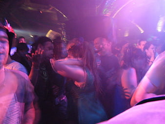 Crowd dancing in a nightclub with purple lighting