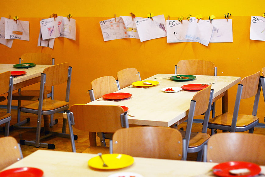 Empty Kindergarten Dining Room with Colorful Plates and Children's Drawings