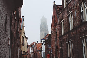 Foggy European Street with Brick Buildings and Distant Tower