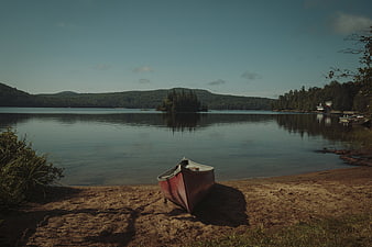 Red Canoe Resting on Sandy Lake Shore