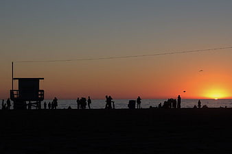 Silhouettes of People on Beach at Sunset with Lifeguard Tower