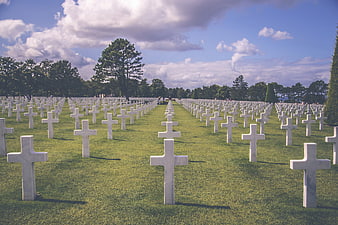 Rows of white crosses in a military cemetery under a blue sky