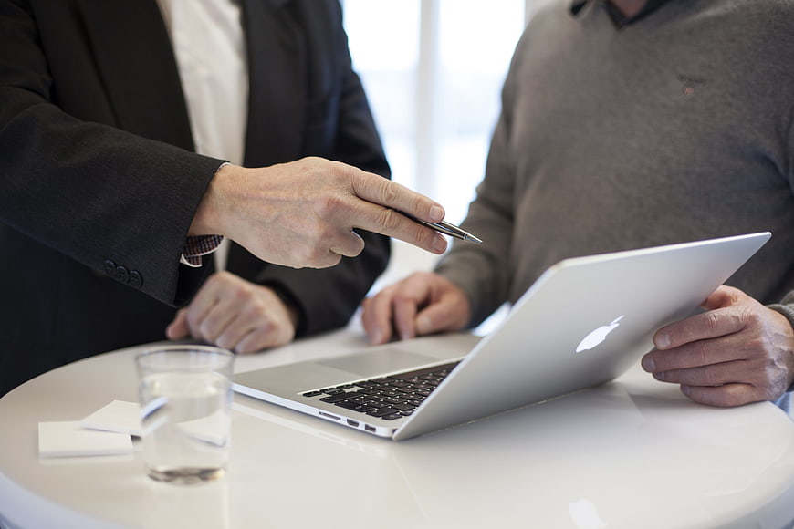 Businessmen discussing work on laptop in office meeting