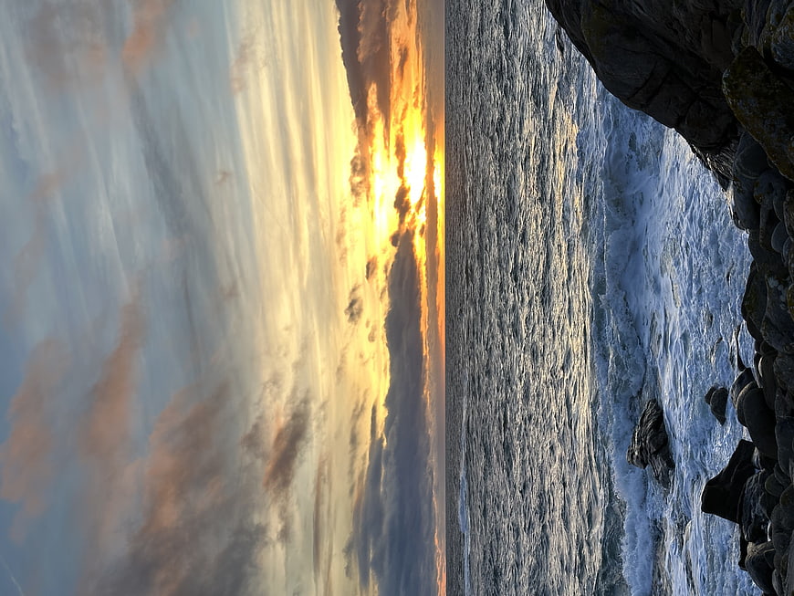 Vertical Sunset Over Ocean Waves and Rocky Coastline