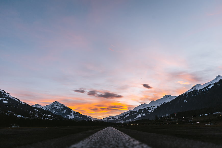 Snowy Mountain Valley Sunset with Leading Road Path