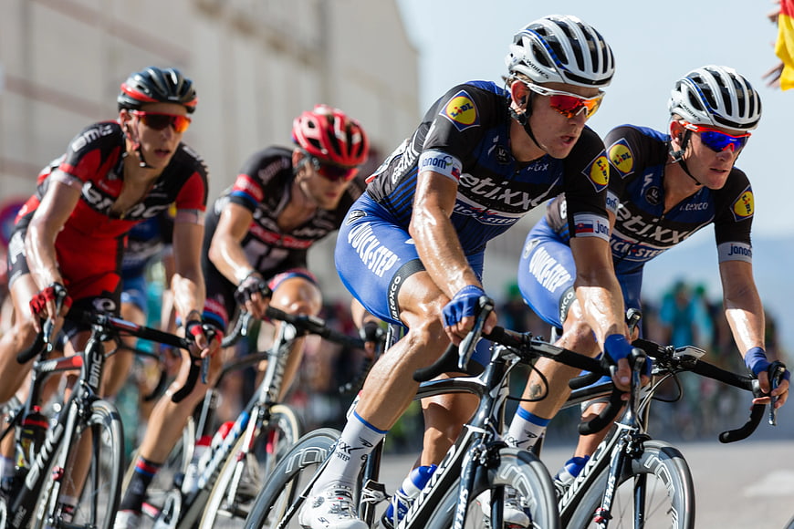 Professional Cyclists Racing on Road in Blue and Red Kits
