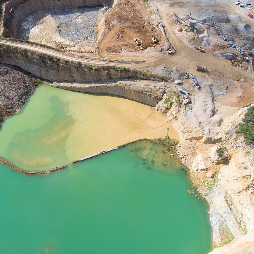 Aerial view of open-pit mine with turquoise water and heavy machinery